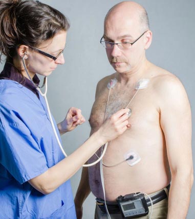 Nurse Listening Man's Heart While Wearing Holter Monitor